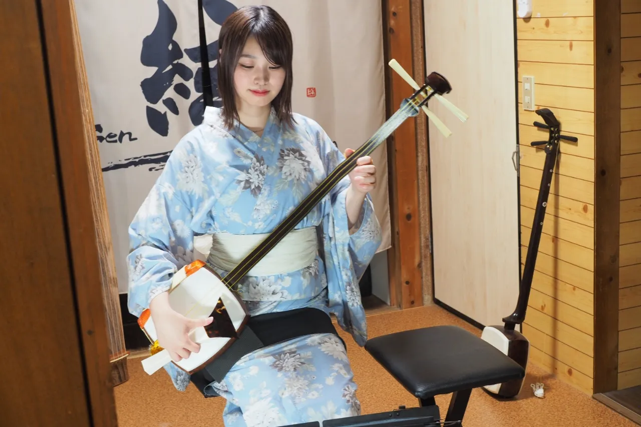 Musician performing shamisen, a Japanese three-stringed lute